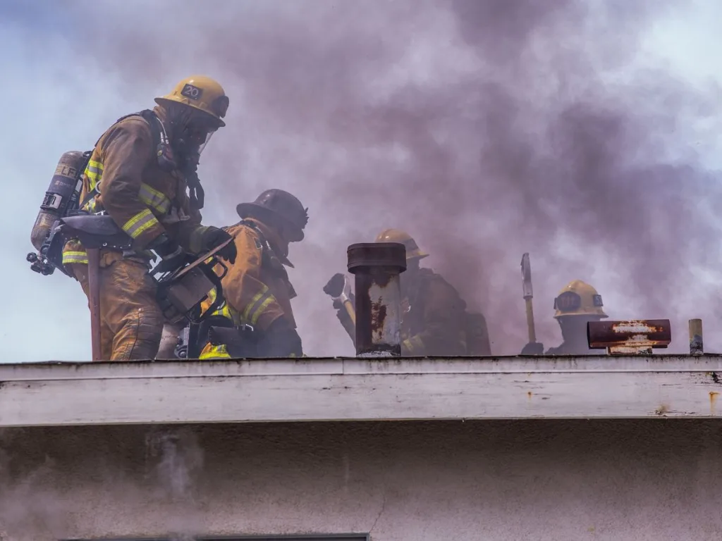 Brandweermannen staan op een dak van een woning een brand te blussen na het afgaan van een rookmelder