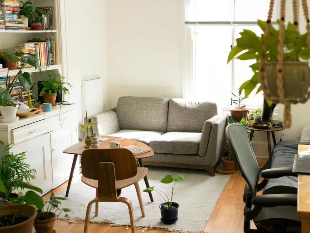 Kleine wonen in een appartement met een grijze bank, salontafel met fauteuil en een bureau en boekenkast moeten ook verzekerd worden met een opstalverzekering
