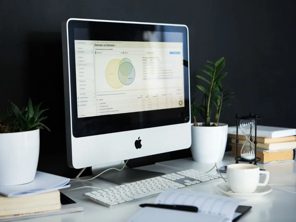 Ergonomisch ingericht bureau met Imac computer, plantjes en een stapel boeken