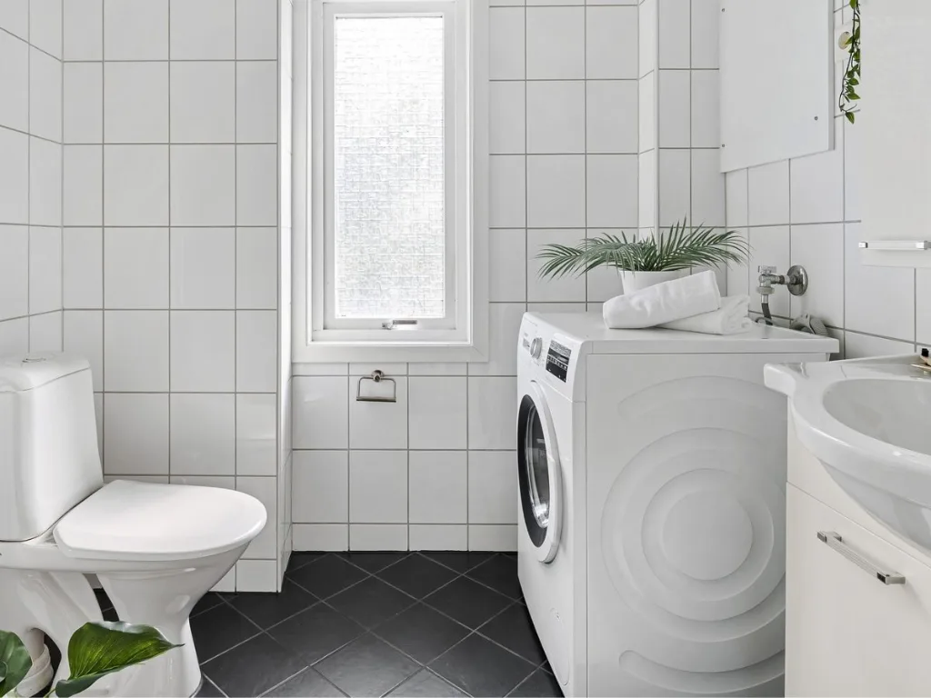 Lichte badkamer met een wasbak, toilet en was-droogcombinatie wasmachine