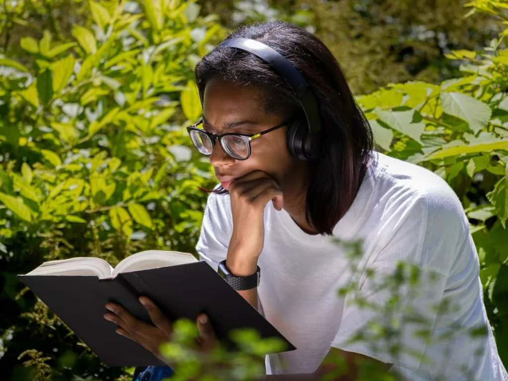 Vrouw met een koptelefoon op lees geconcentreerd een boek terwijl ze luistert naar focus muziek
