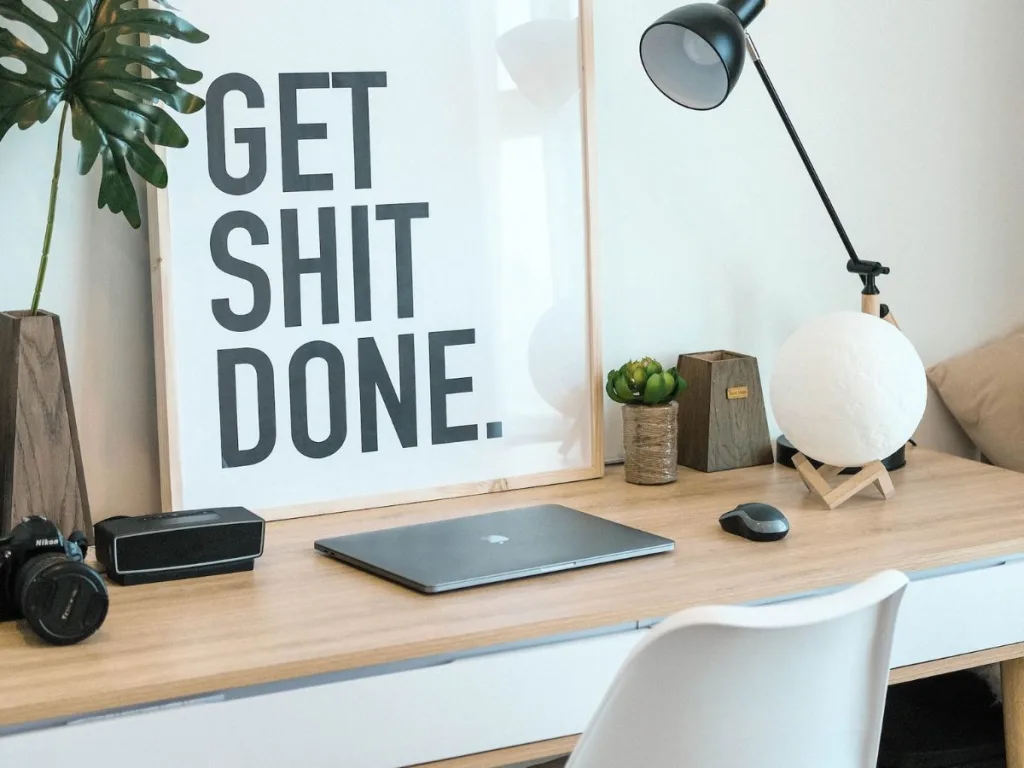 Bureau met een laptop en een schilderij met de tekst get shit done