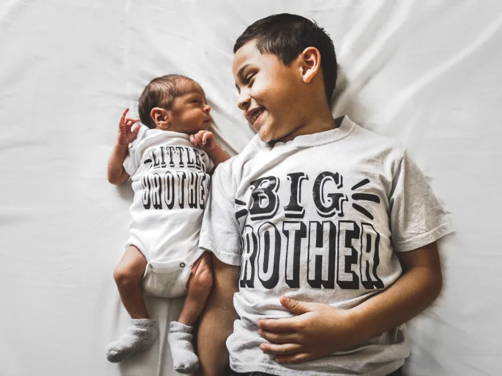 Grote broer poseert met baby broertje voor een geboorte fotoshoot