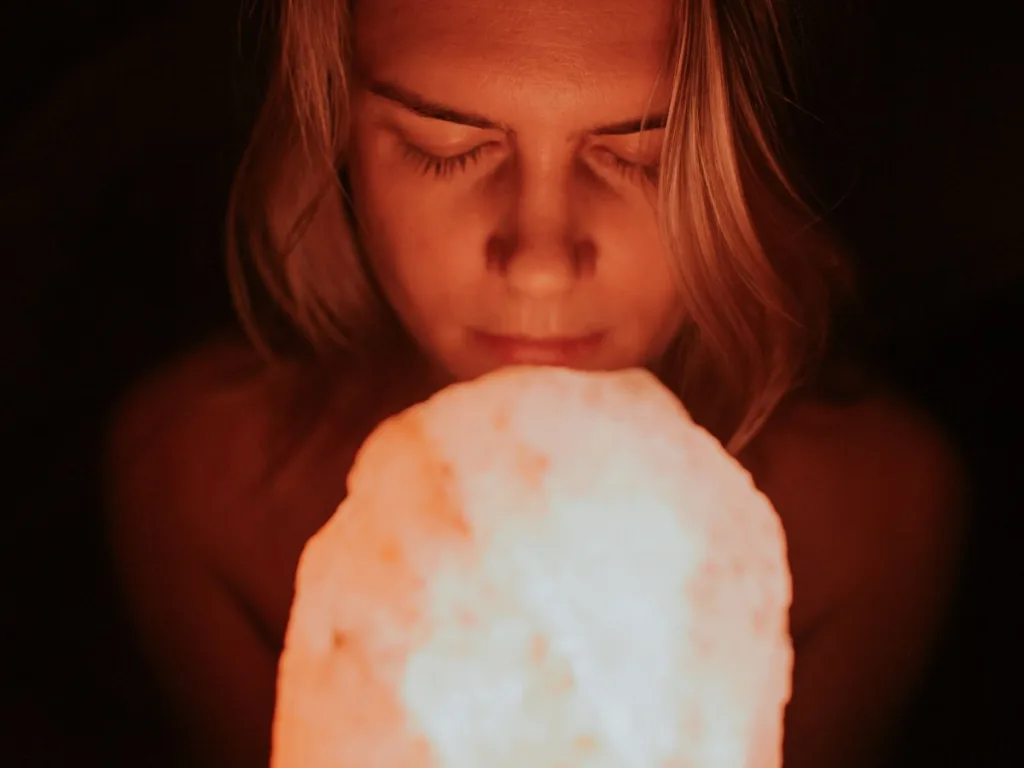 Vrouw houdt een zoutlamp vast onder haar gezicht