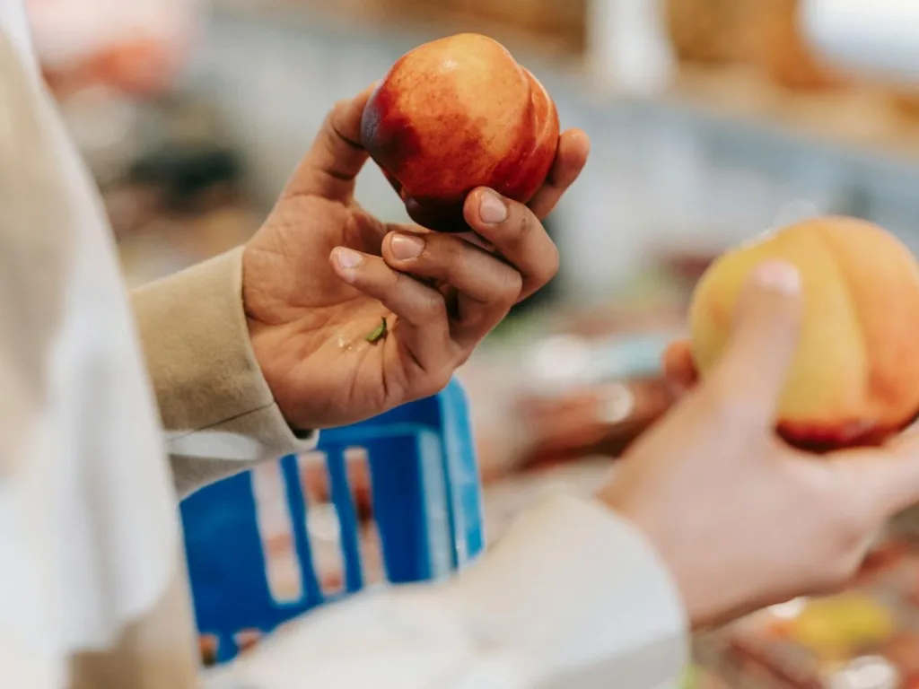 Man staat in de supermarkt met een boodschappenmandje en fruit in zijn handen