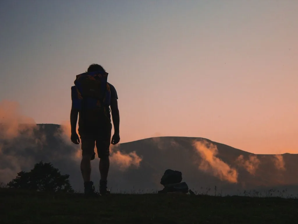 Man staat op een bergtop na het maken van een lange wandeling