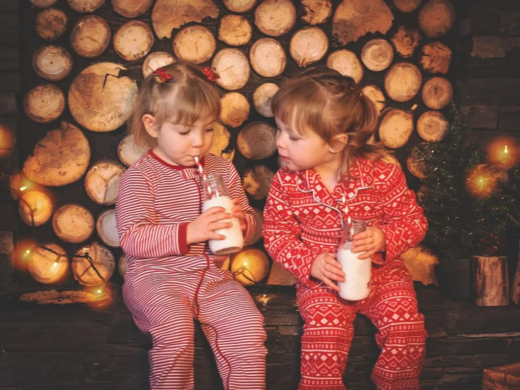 Twee meisjes zitten met Oud en Nieuw een drankje te drinken in een knusse woonkamer