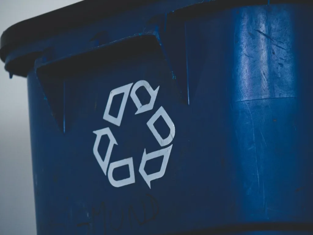 Blauwe afvalbak met een recycle logo op de zijkant