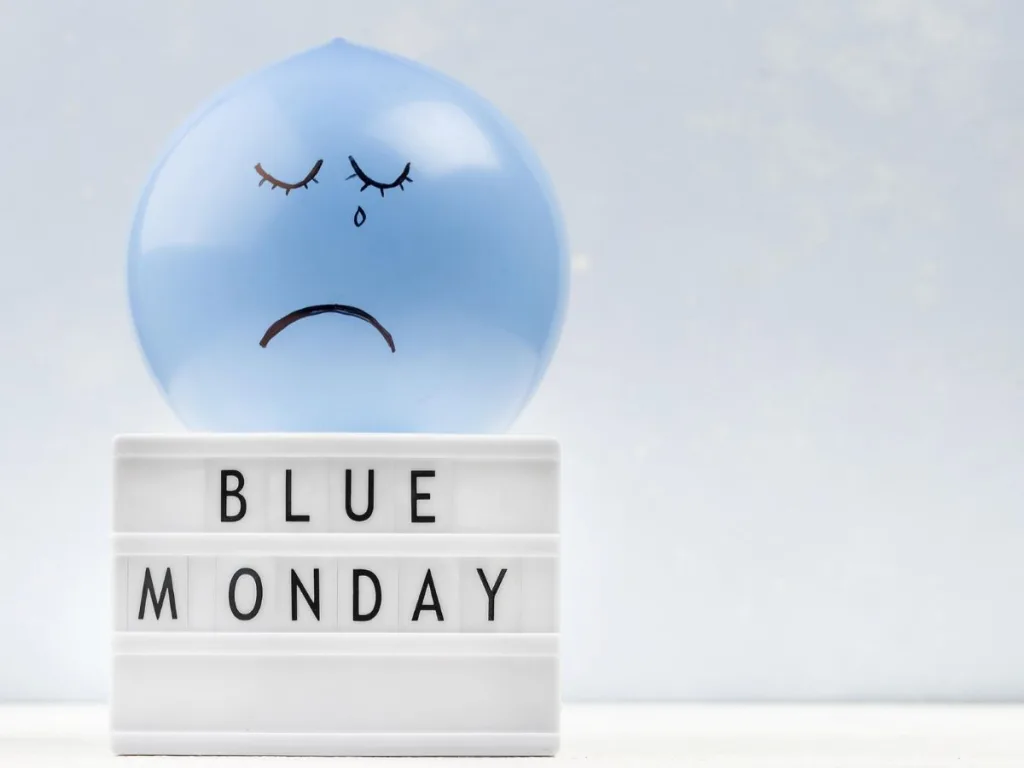 Blauwe ballon met een verdrietig gezicht erop en daaronder de tekst Blue Monday