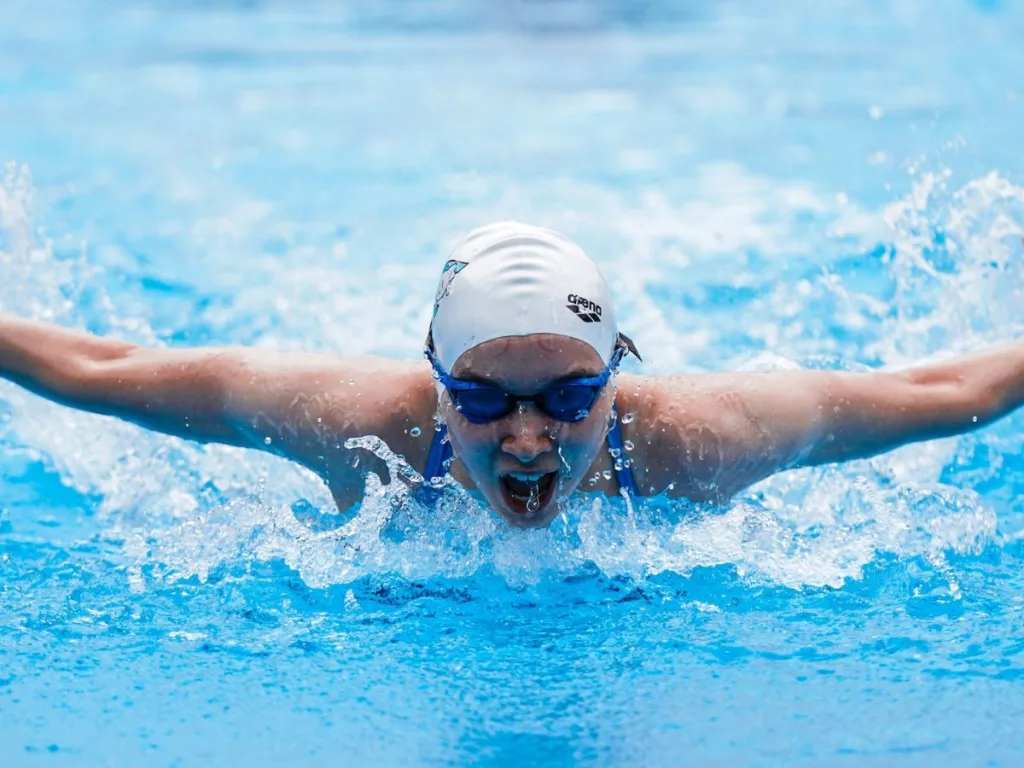 Man in zwembad met badmuts en zwembril op