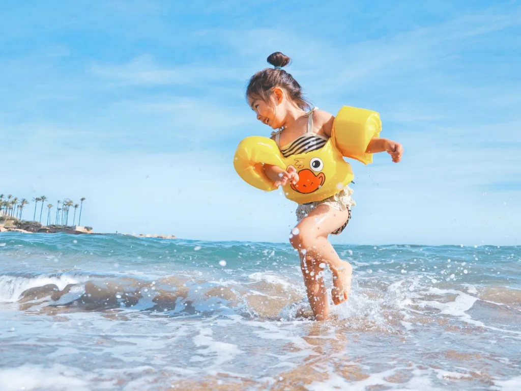 Meisje met zwembandjes speelt in de zee op vakantie tijdens de zomervakantie