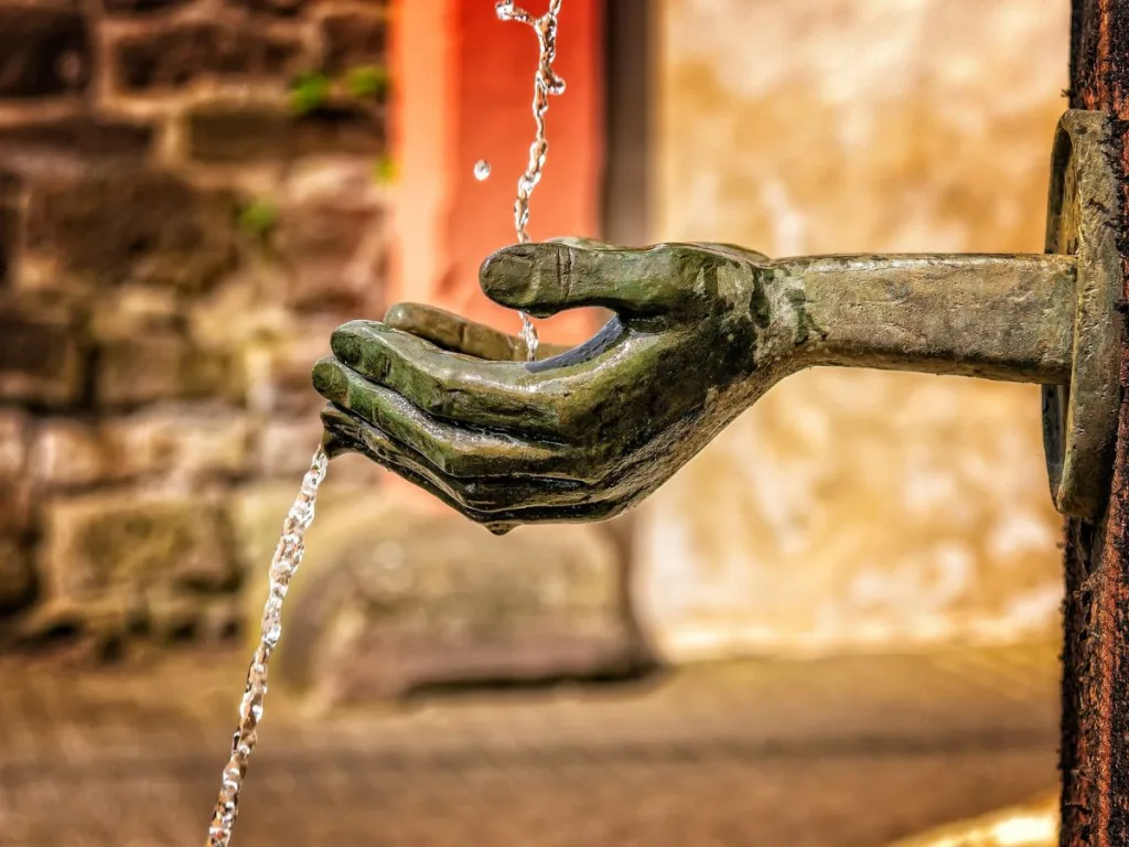 Fontijn beeld met twee handen uitgestoken die water opvangen om te kunnen drinken