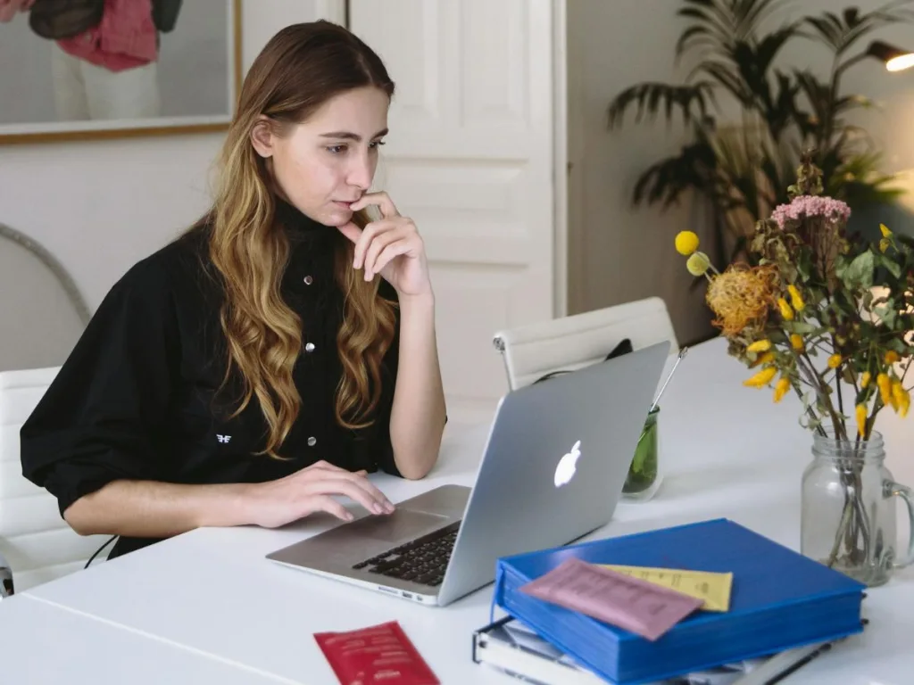 Vrouw zit met een laptop aan de keukentafel hybride te werken