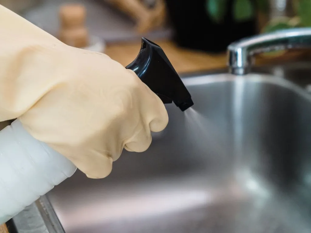 Hand met sprayfles die de keuken aan het schoonmaken is tijdens de voorjaarsschoonmaak