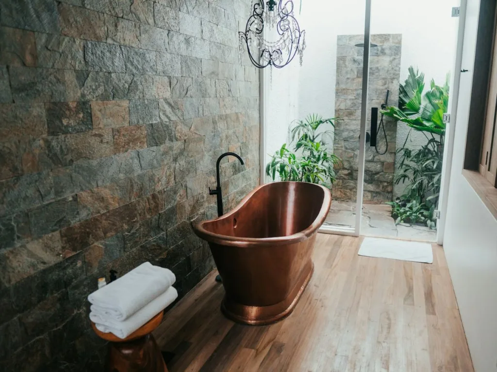 Donkere wellness badkamer met een luxe koperen bad en luxe inloopdouche