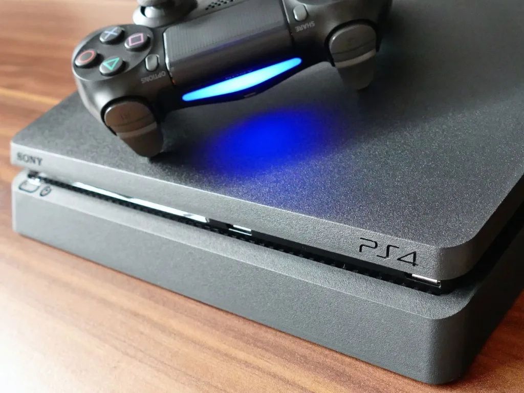 Zwarte PlayStation 4 spelcomputer met een zwarte controller er bovenop op een tafel