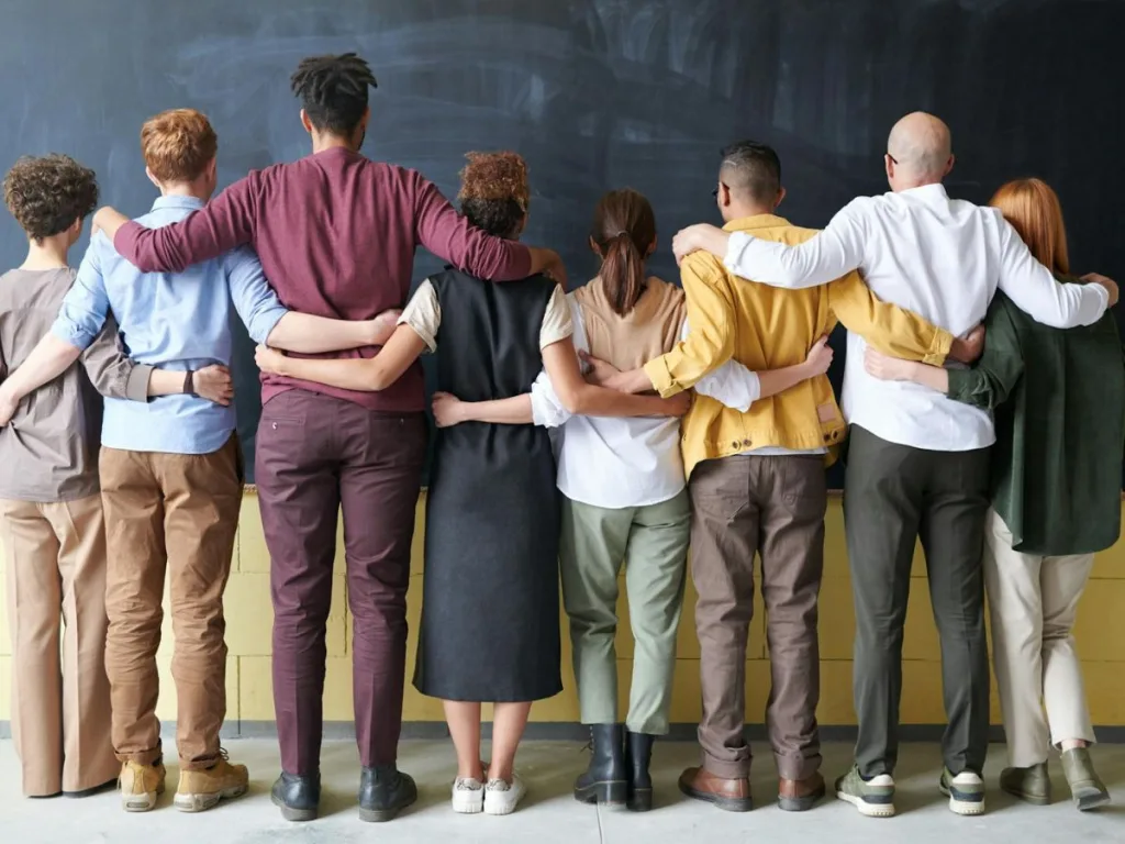 Groep tevreden medewerkers vormen een hecht team door met de armen om elkaar heen op een rij te staan